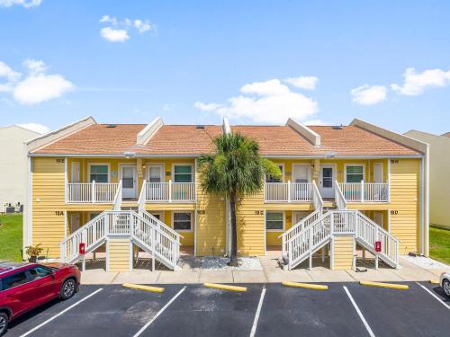 a yellow apartment building with a palm tree in a parking lot at C' Salt 10B in Destin
