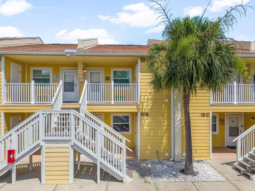 a yellow house with white stairs and a palm tree at C' Salt 10B in Destin
