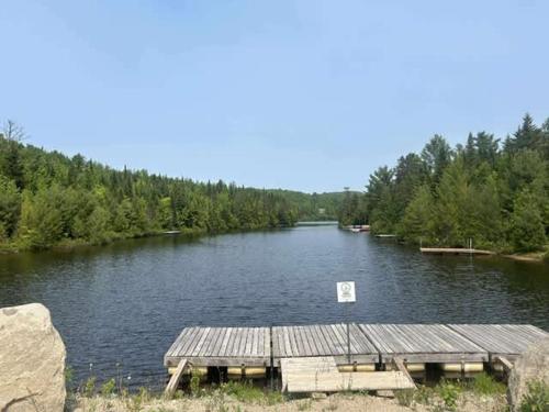a dock on a river with a sign in the water at Chalet Origine St-Come - SPA in Saint Come