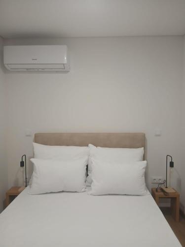 a bedroom with a white bed with white pillows at Casinhas do Campo by Gerês Valley in Campo do Gerês