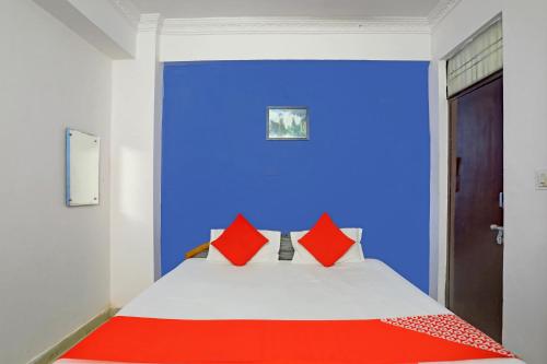 a blue room with a bed with red pillows at Hotel O APM Palace in Hasanganj