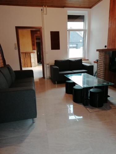 a living room with a couch and a glass table at Une chambre chez l'habitant près de l'aéroport de Charleroi in Charleroi