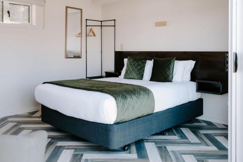 a bedroom with a large bed with white sheets and green pillows at Te Mata Views Resort in Havelock North