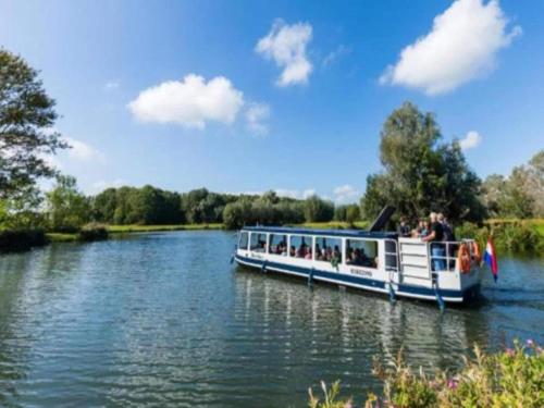 a boat on a river with people on it at Bungalow in South Holland by the Water in Simonshaven