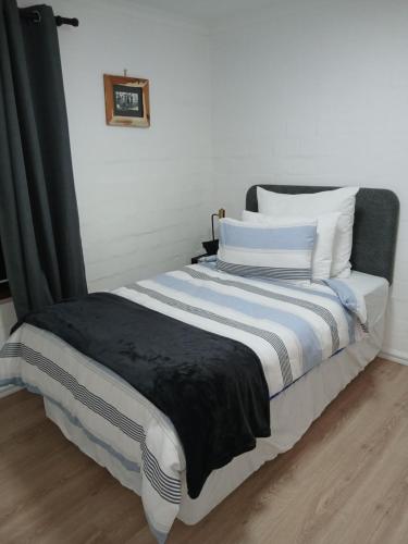a bed with black and white sheets and pillows at Fisherman's Haven in Bloubergstrand