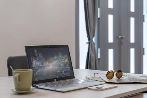 a laptop computer sitting on a desk with a cup of coffee at Valentini Luxury Loft-18 by train to Florence-PARKING FREE in Prato