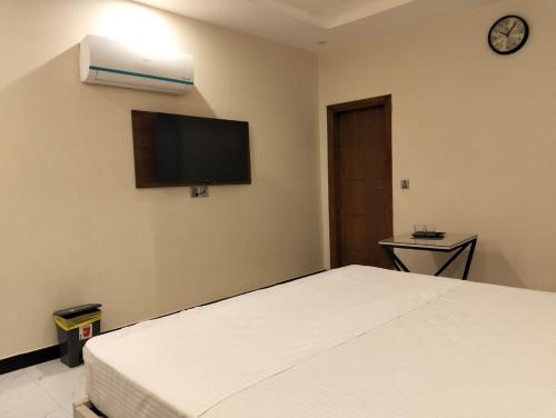 a bedroom with a bed and a tv on the wall at Dove INN Express in Lahore