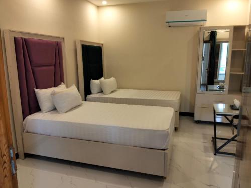 a hotel room with two beds and a mirror at Dove INN Express in Lahore