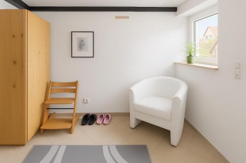 a living room with a white chair and shoes at Gemütliche 2-Zimmer Wohnung 50qm in Reckershausen