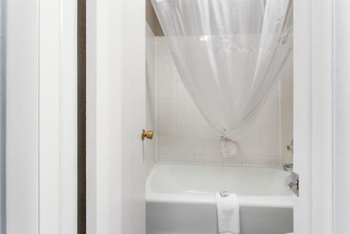 un bagno bianco con vasca e tenda per la doccia di Studio 6 Suites Butte MT I-90 I-15 a Butte