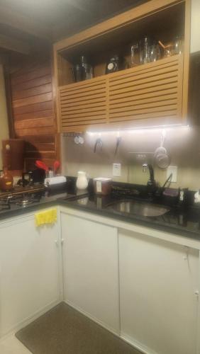 a kitchen with white cabinets and a sink at Chalé dos Manacás Duplex in Venda Nova do Imigrante