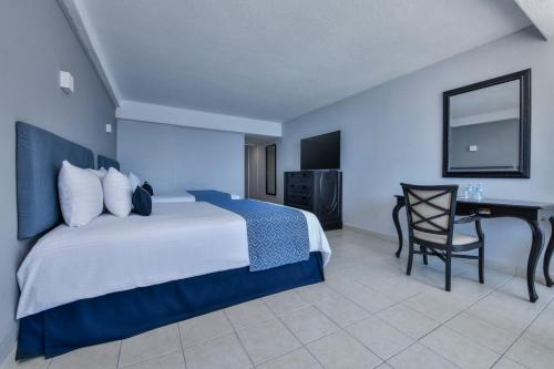 a hotel room with a bed and a desk at Krystal Beach Acapulco in Acapulco
