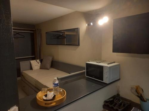 a small room with a bed and a microwave at Le Cocon Studio in Clermont