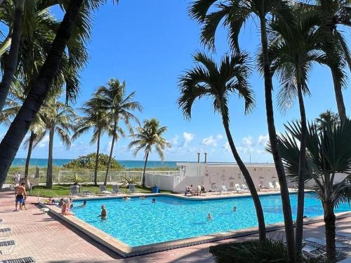 マイアミビーチにあるOceanfront Studios Miami Beachのヤシの木と人々が泳ぐスイミングプール