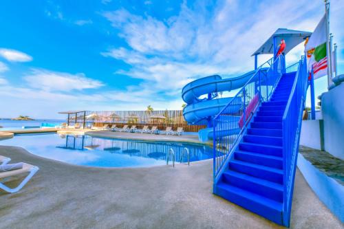 a blue water slide next to a swimming pool at Krystal Beach Acapulco in Acapulco