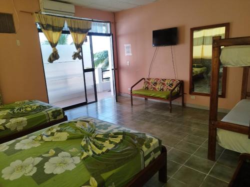 a bedroom with two beds and a television and a chair at RS Hotel Granada in Atacames