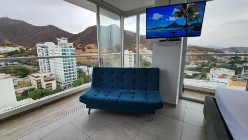 a blue chair in a room with a large window at Hermoso Apartamento con doble vista Mar y montaña tipo Loft cerca a la playa instalaciones nuevas in Gaira