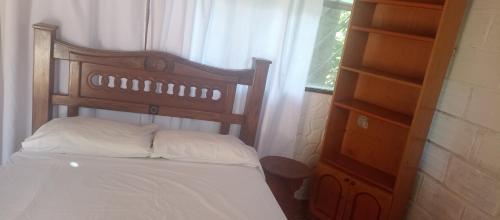 a bed with a wooden headboard and a window at Spa Campestre Los Vedas in Santa Marta