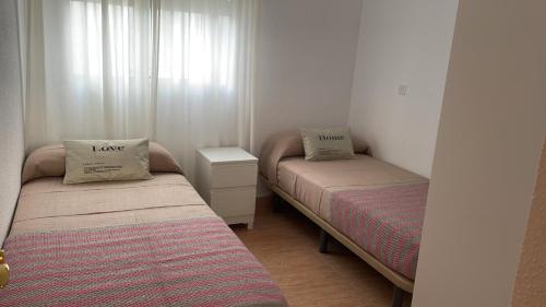 two beds in a small room with two pillows on them at Piso acogedor en Barbate in Barbate