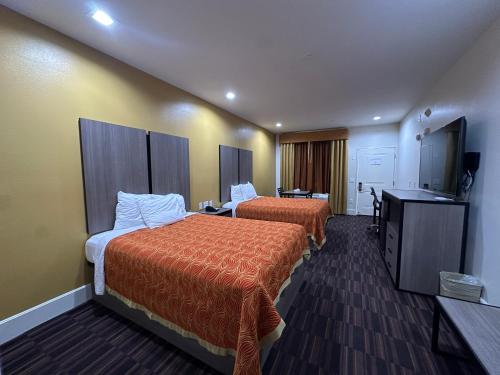 ケイティーにあるScottish Inn and Suitesのベッド2台と薄型テレビ付きのホテルの部屋