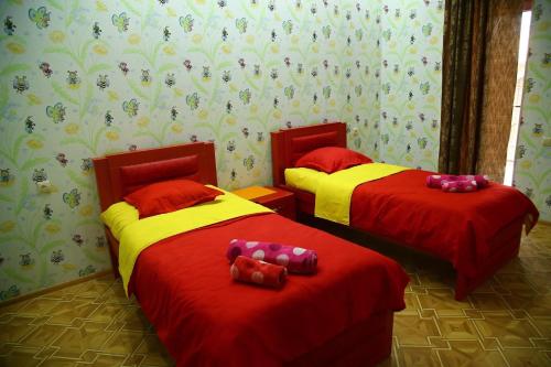 two beds in a room with red and yellow sheets at Hotel Meskhuri Oda in Akhaltsikhe