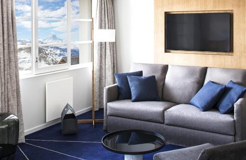 a living room with a couch and a tv at White 1921 Courchevel in Courchevel