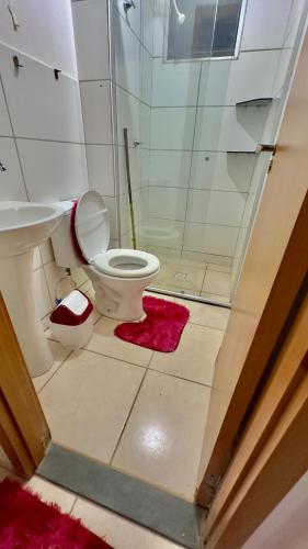 a bathroom with a toilet and a red rug at Só 1 Quarto Belle Nature in Valparaíso de Goiás