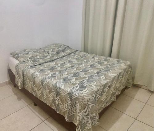 a bed with a comforter on it in a bedroom at Só 1 Quarto Belle Nature in Valparaíso de Goiás