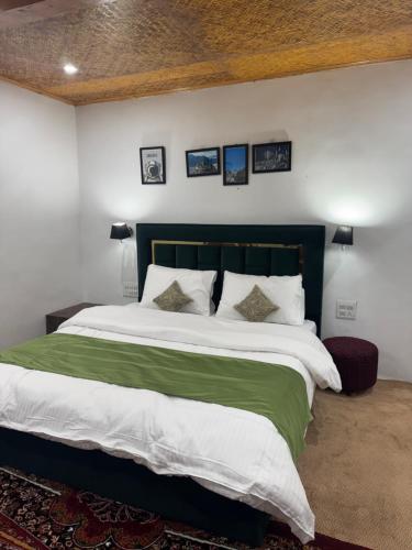 Schlafzimmer mit einem großen Bett mit grüner und weißer Bettwäsche in der Unterkunft EVERGREEN ESCAPE in Kargil