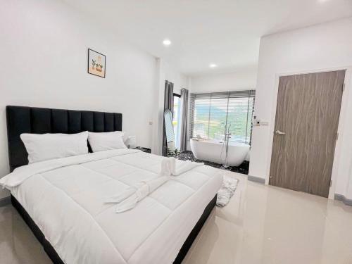 a bedroom with a large white bed and a bath tub at บ้านพักเขาใหญ่ ลูกแก้วพูลวิลล่า Lookkaew Pool Villa Khaoyai in Ban Rai Khlong Sai