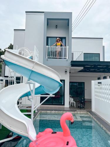a woman standing on the balcony of a house with a swimming pool at บ้านพักเขาใหญ่ ลูกแก้วพูลวิลล่า Lookkaew Pool Villa Khaoyai in Ban Rai Khlong Sai