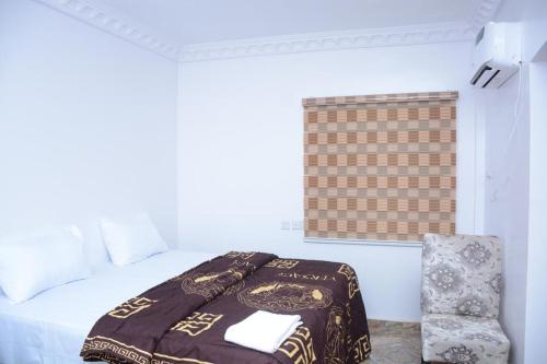 a bed with a blanket and a chair in a room at High-Con Hotel and Suites in Mama