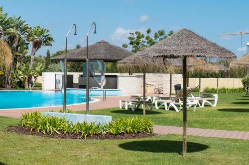a resort with a pool and chairs and umbrellas at Victoria Boulevard in Vilamoura