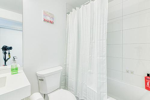 a white bathroom with a toilet and a shower at RivetStays - The Jarvis in Toronto