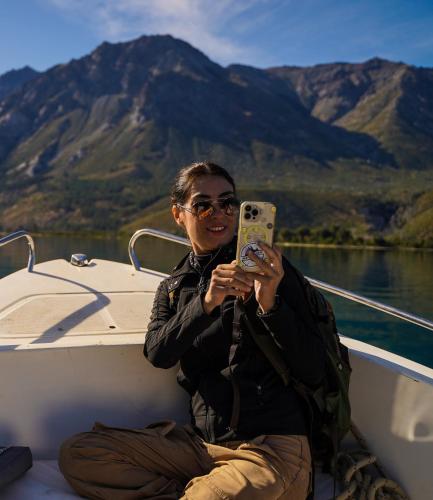 a man sitting on a boat holding a cell phone at Monte del Tigre Adventure Lodge in Cholila
