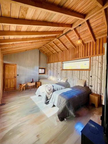 a bedroom with two beds in a room with wooden ceilings at Monte del Tigre Adventure Lodge in Cholila