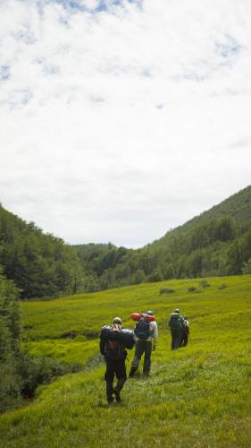 a group of people walking in a grassy field at Monte del Tigre Adventure Lodge in Cholila