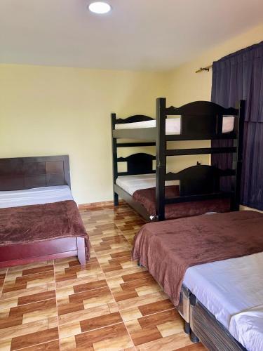 a bedroom with two bunk beds and a wooden floor at Hotel Campestre Villa Alicia in Estación El Salto
