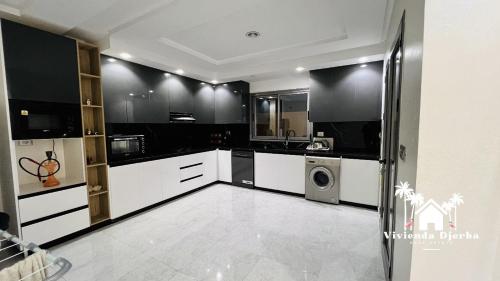 a kitchen with white cabinets and a washer and dryer at Djerba Villa De Luxe in Houmt Souk