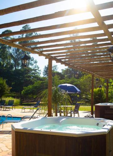 a large hot tub under a wooden pergola at Stallage Hotel in São Pedro