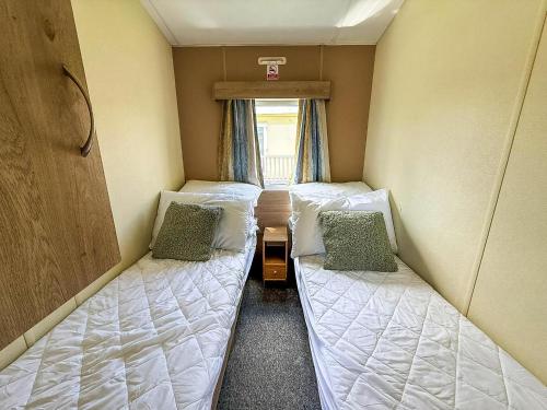twee bedden in een kleine kamer met een raam bij Lovely 8 Berth Caravan At Southview Holiday Park, Skegness Ref 33023M in Skegness
