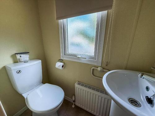 een badkamer met toilet, wastafel en raam bij Lovely 8 Berth Caravan At Southview Holiday Park, Skegness Ref 33023M in Skegness