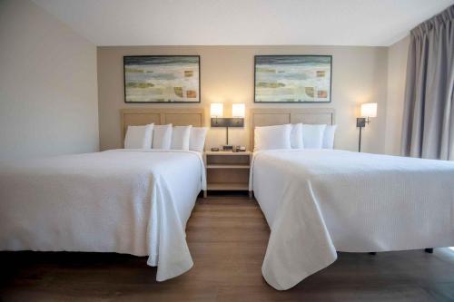two beds in a hotel room with white sheets at Extended Stay America Suites - Phoenix - Biltmore in Phoenix
