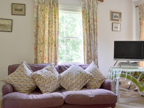 a purple couch with pillows in a living room with a window at Sunnybank in Saint Margaret