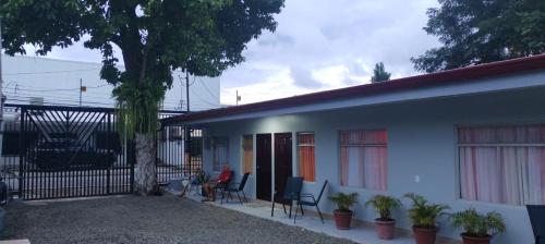 a white house with chairs and a tree at Cabinas Doña Alicia in Quepos