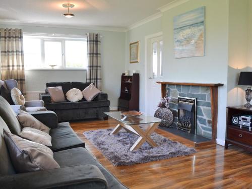 a living room with a couch and a fireplace at Encil-Y-Mor in Criccieth