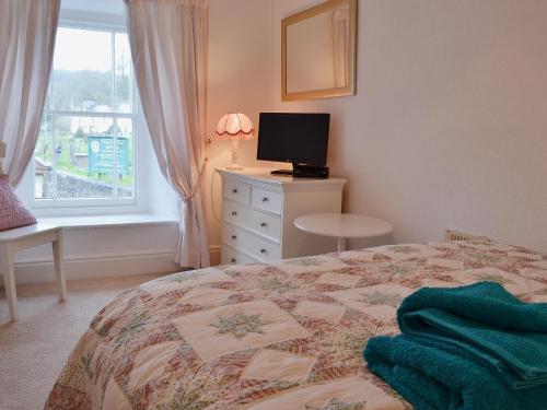 a bedroom with a bed and a television and a window at The Old Post Office in Myddfai