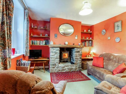 ein Wohnzimmer mit orangefarbenen Wänden und einem Kamin in der Unterkunft Old Orchard Cottage in Dilton