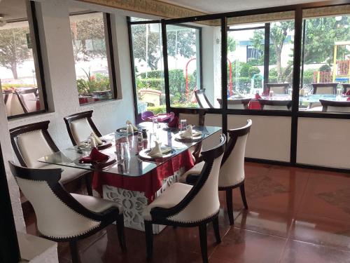 a dining room with a table and chairs and windows at Hostería El Prado in Ibarra