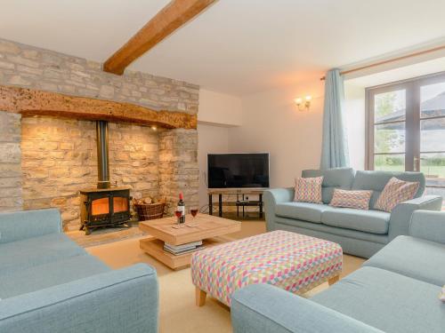 a living room with two blue couches and a fireplace at Mulberry Cottage in North Wootton